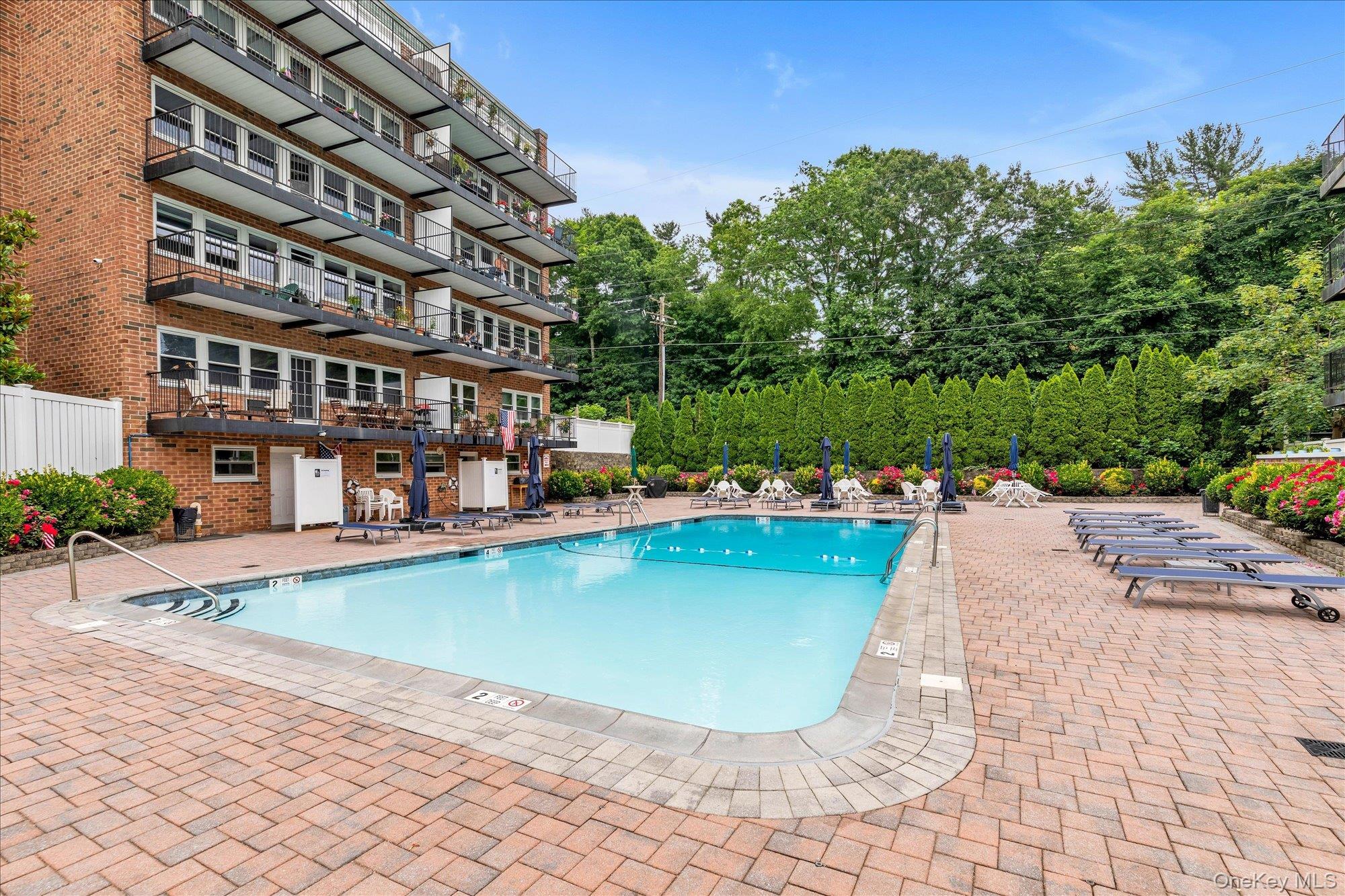 30 Pearsall Avenue, Unit 2F Glen Cove, NY 11542 - Photo 23 of 25 Community pool featuring a patio area and view of scattered trees