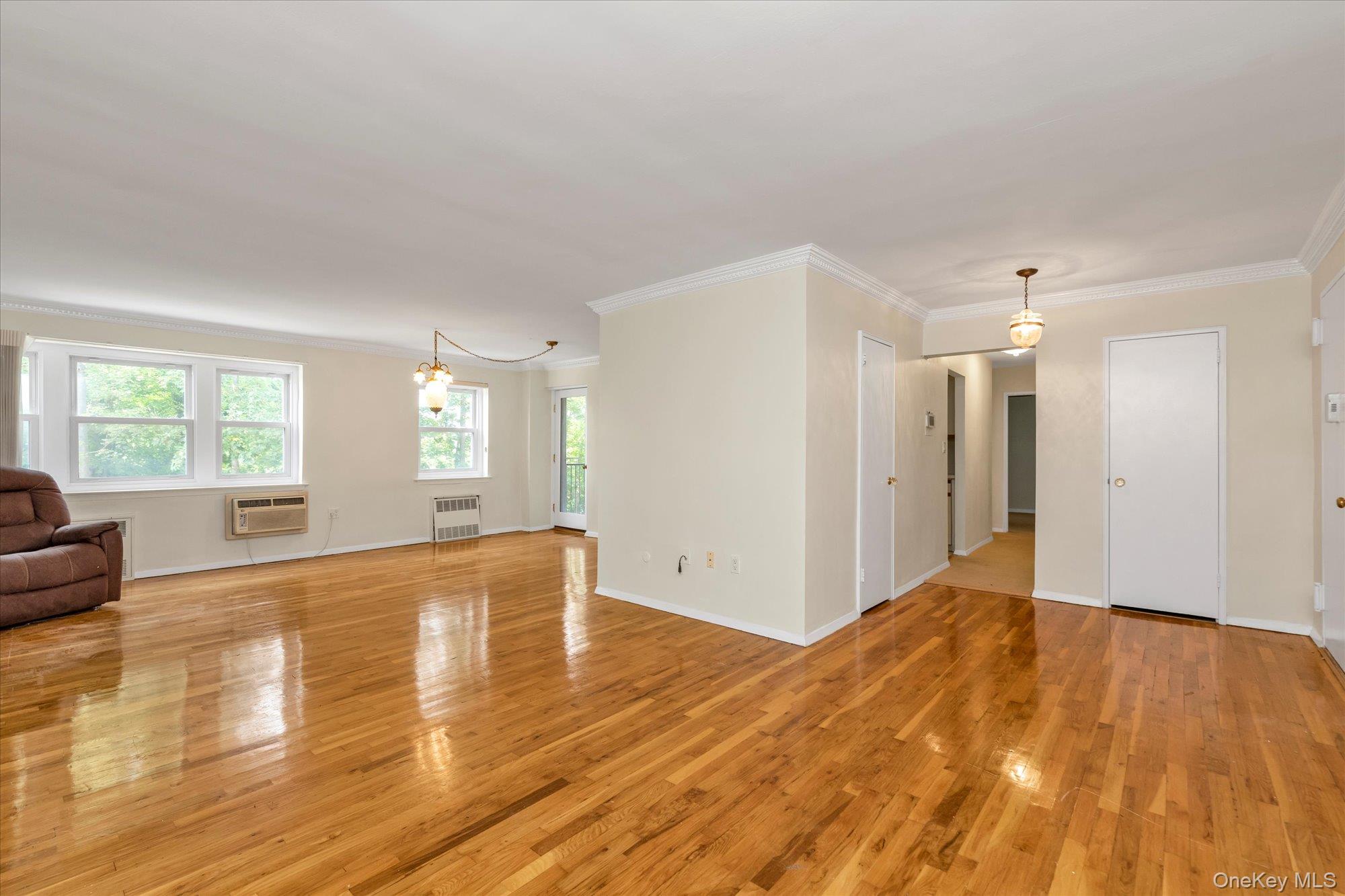30 Pearsall Avenue, Unit 2F Glen Cove, NY 11542 - Photo 4 of 25 Spare room with ornamental molding, light wood-style floors, healthy amount of natural light, a chandelier, and radiator heating unit