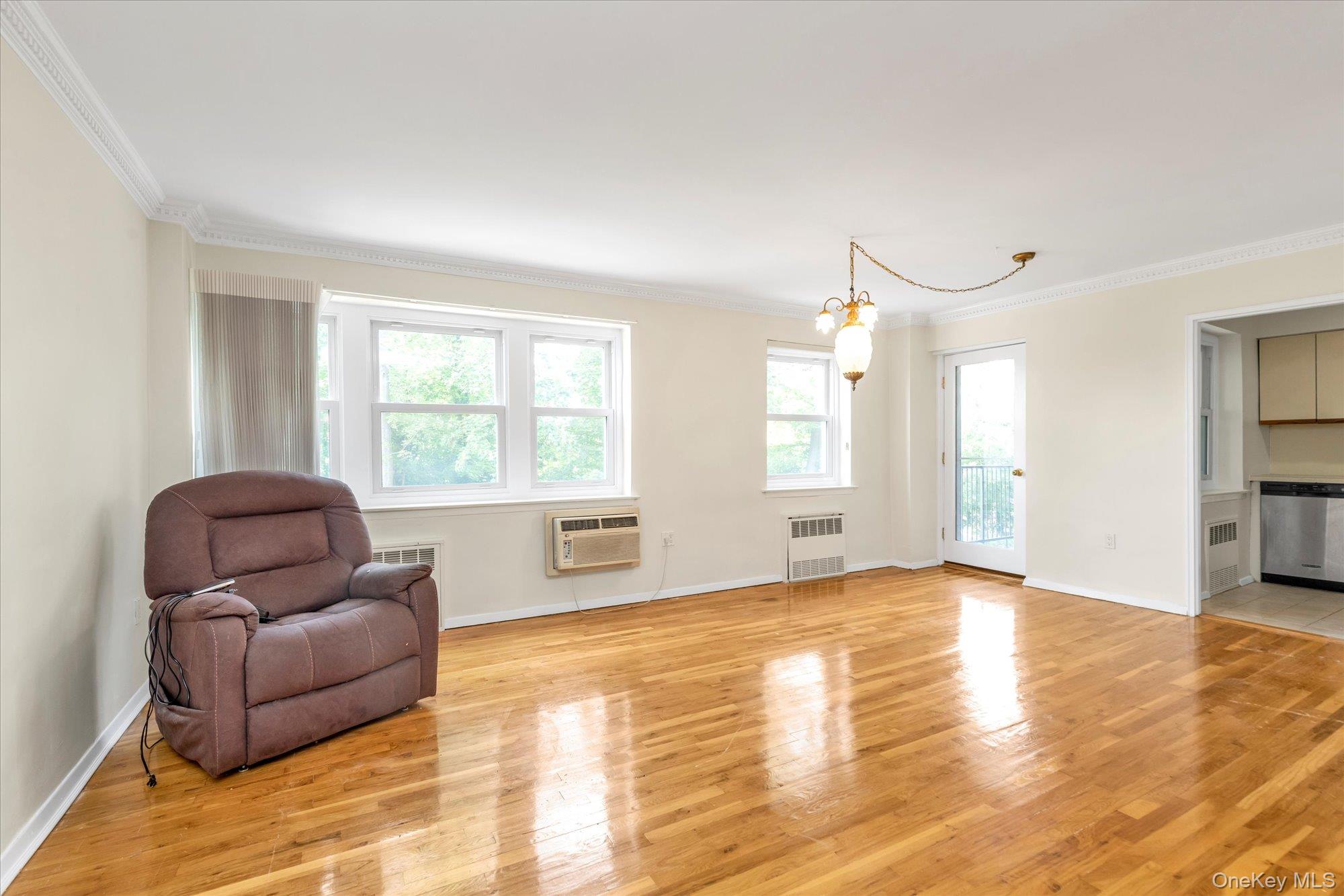 30 Pearsall Avenue, Unit 2F Glen Cove, NY 11542 - Photo 8 of 25 Living area with crown molding, a chandelier, light wood-style floors, and radiator heating unit