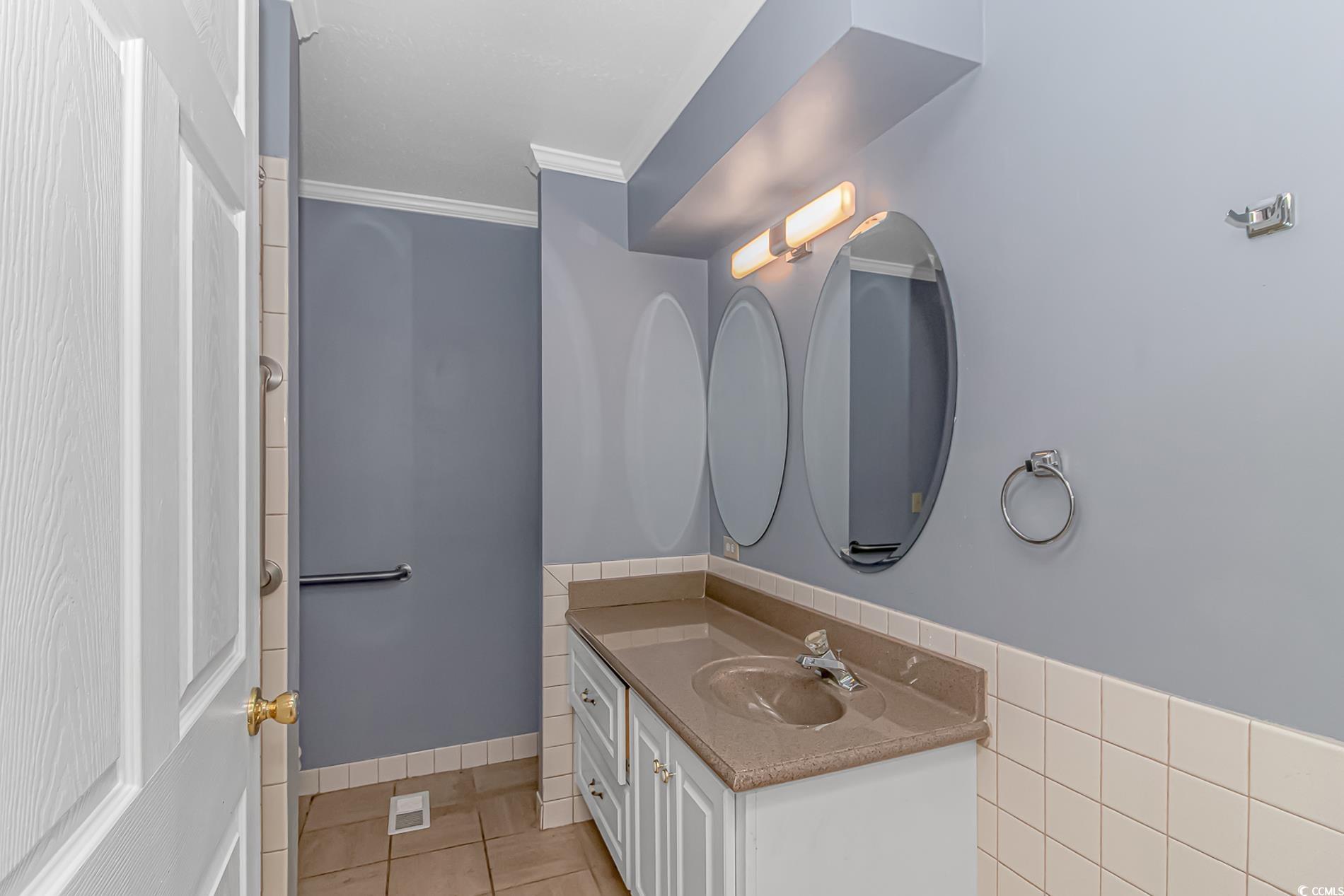 2829 Highway 129 Galivants Ferry, SC 29544 - Photo 13 of 40 Bathroom featuring tile patterned flooring, vanity, tile walls, crown molding, and a wainscoted wall