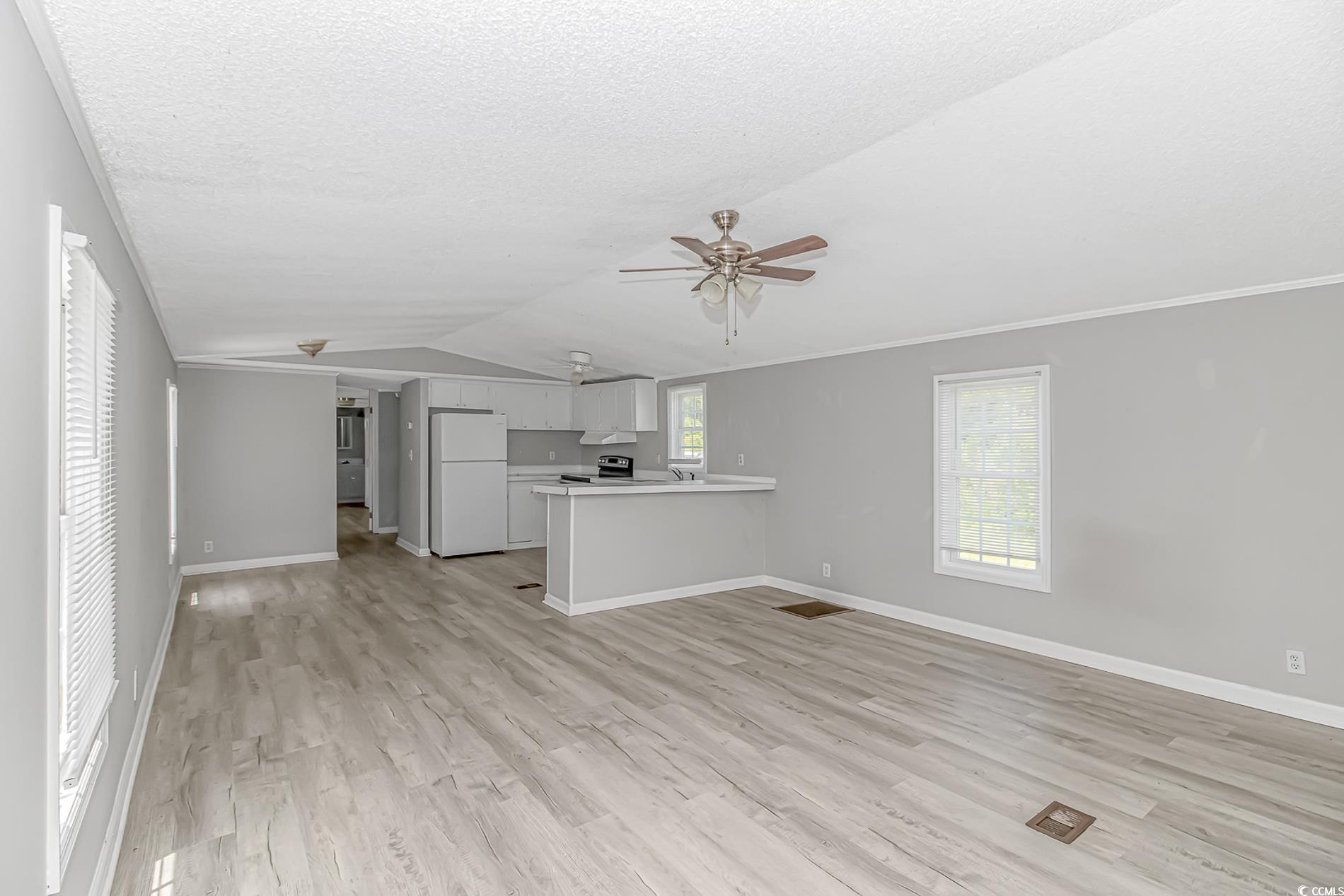 2829 Highway 129 Galivants Ferry, SC 29544 - Photo 26 of 40 Unfurnished living room with ceiling fan, light wood-style flooring, lofted ceiling, a textured ceiling, and crown molding
