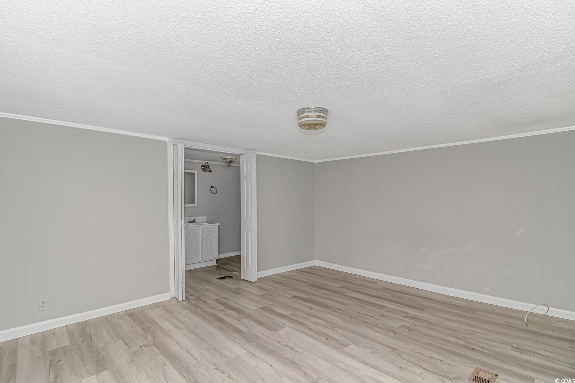 2829 Highway 129 Galivants Ferry, SC 29544 - Photo 28 of 40 Empty room with light wood finished floors, a textured ceiling, and ornamental molding