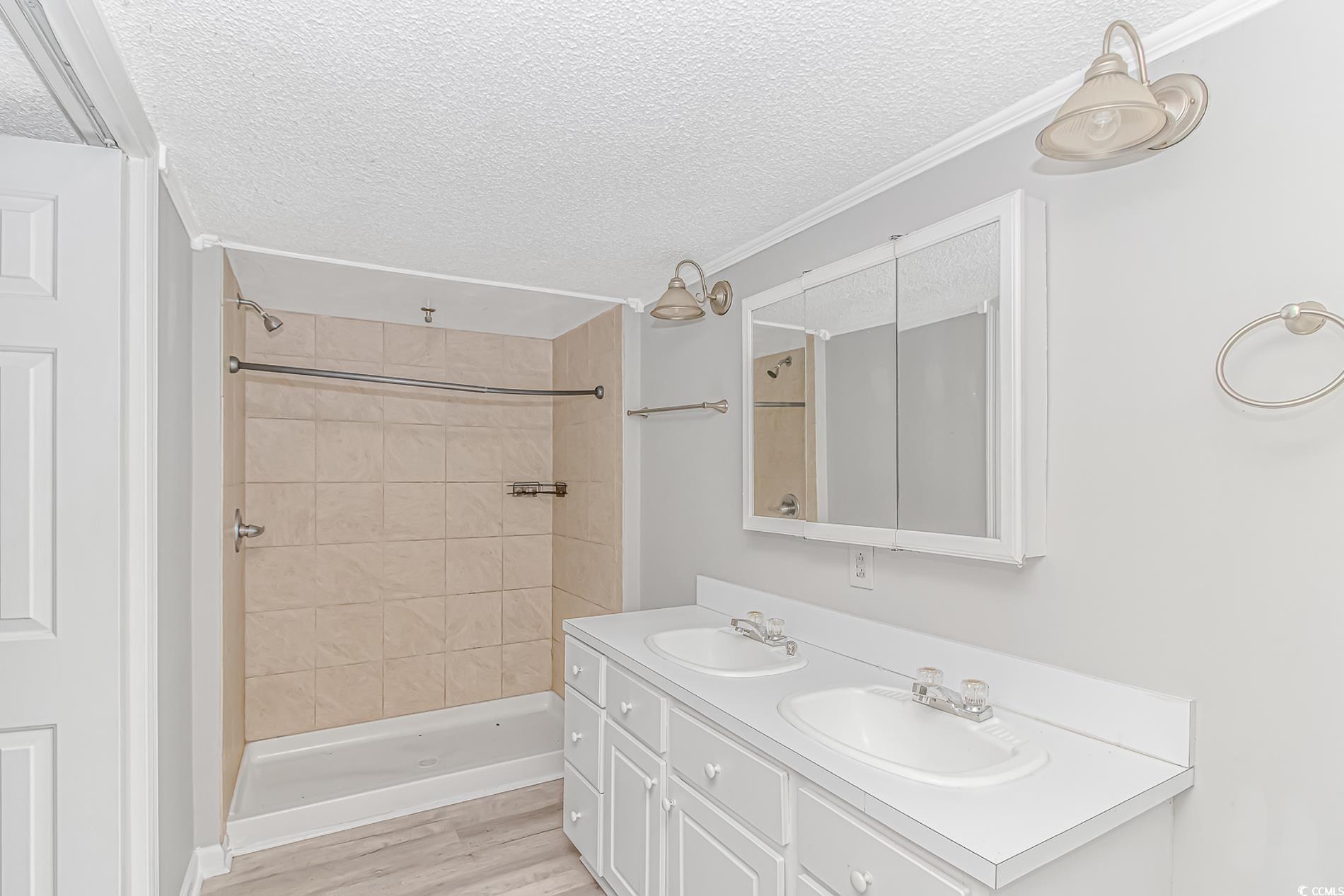 2829 Highway 129 Galivants Ferry, SC 29544 - Photo 29 of 40 Bathroom with a textured ceiling, double vanity, tiled shower, crown molding, and wood finished floors