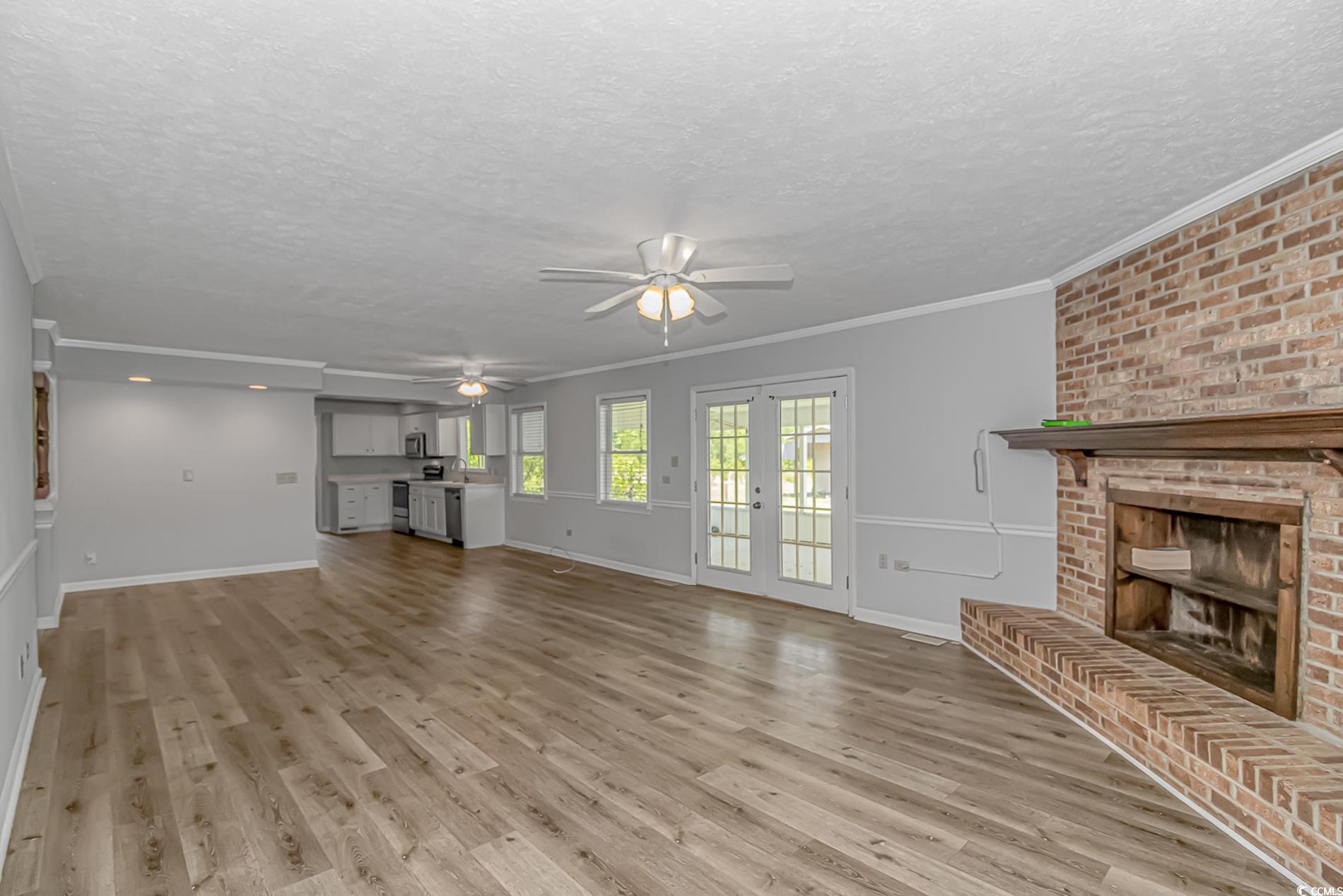 2829 Highway 129 Galivants Ferry, SC 29544 - Photo 5 of 40 Unfurnished living room with light wood-style floors, ceiling fan, a textured ceiling, a fireplace, and ornamental molding