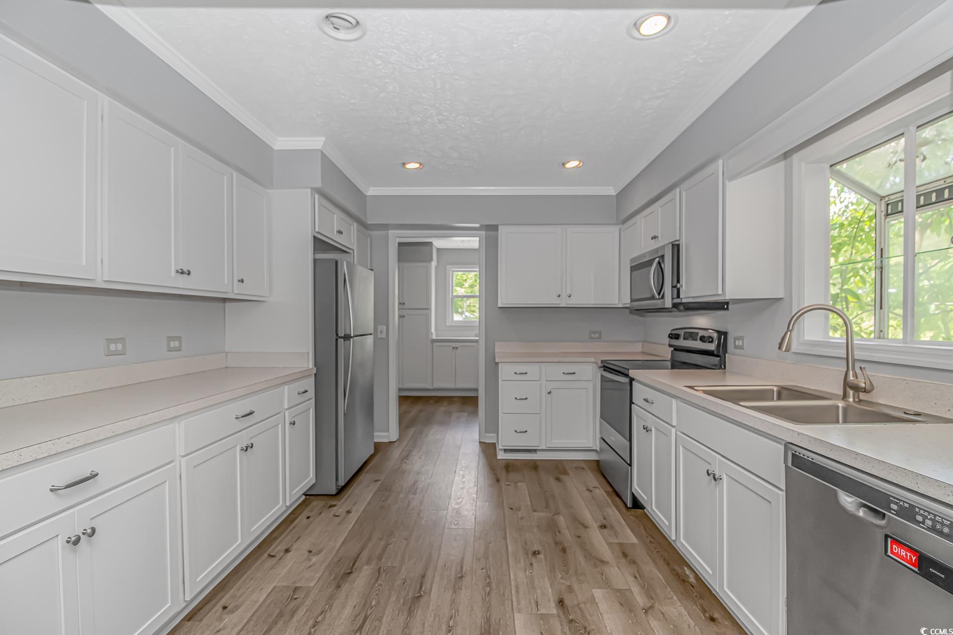 2829 Highway 129 Galivants Ferry, SC 29544 - Photo 6 of 40 Kitchen featuring stainless steel appliances, white cabinetry, ornamental molding, light countertops, and light wood-style flooring