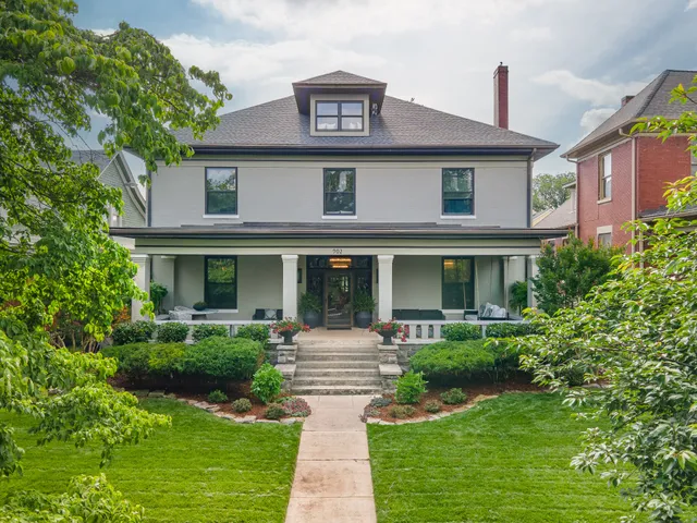 a front view of a house with garden and trees