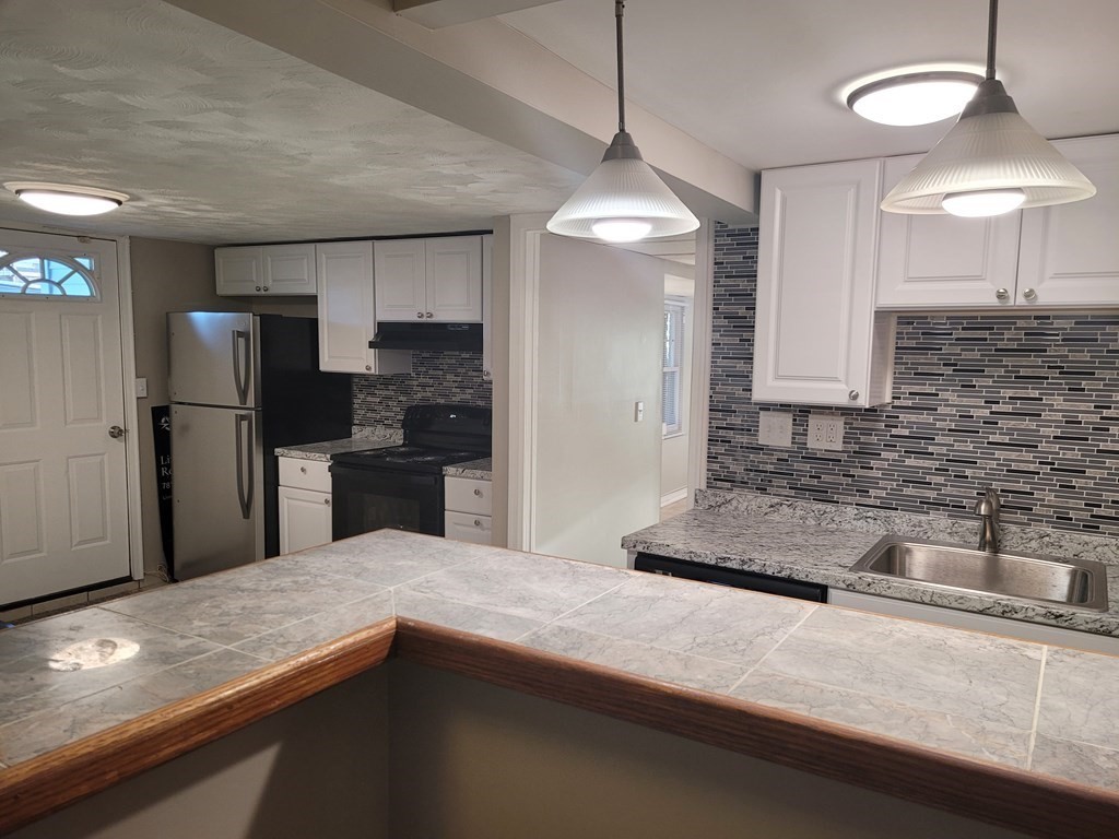 a kitchen with stainless steel appliances granite countertop a sink a refrigerator and a granite counter tops