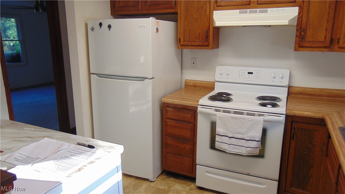 4970 Bryenton Road Litchfield, OH 44253 - Photo 13 of 33 Kitchen featuring white appliances, light countertops, under cabinet range hood, and brown cabinetry