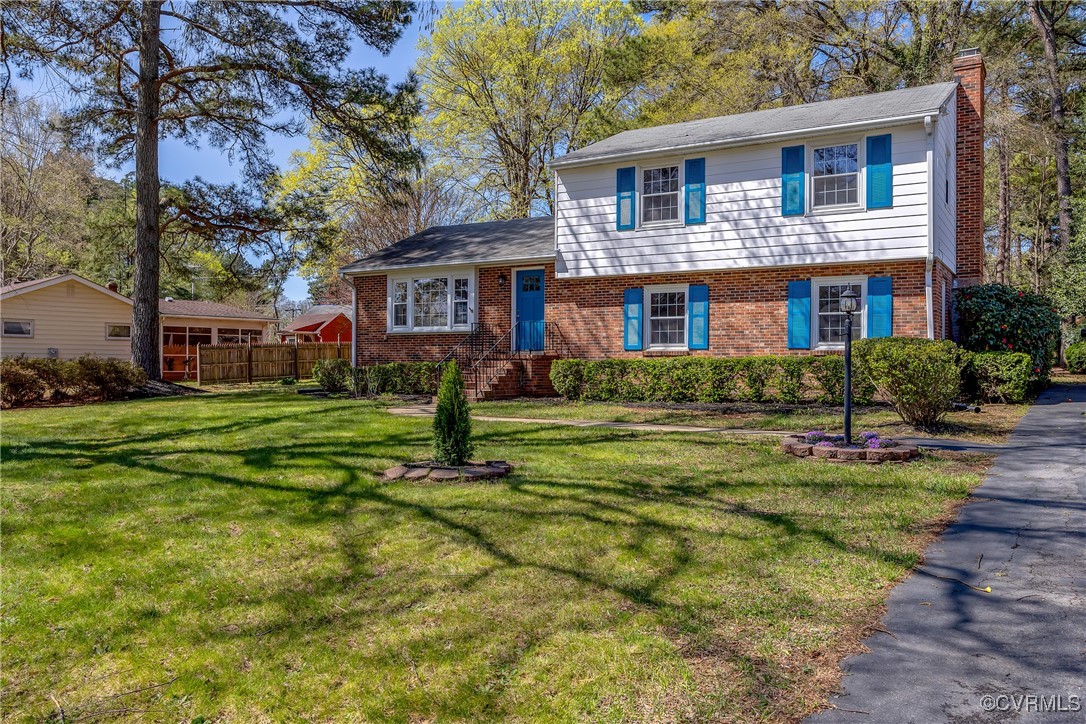 Split level home featuring a chimney, a front yard