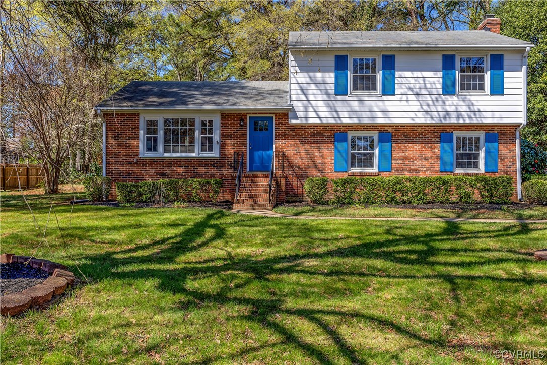 Split level home with brick siding, a front yard,