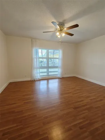 an empty room with wooden floor and a ceiling fan