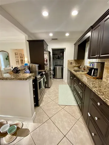 a large kitchen with stainless steel appliances granite countertop a sink stove and cabinets