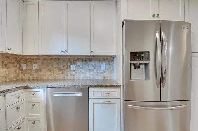 a kitchen with stainless steel appliances granite countertop a refrigerator a sink a stove and white cabinets