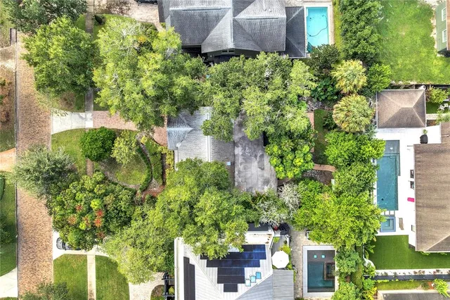 an aerial view of a residential houses with outdoor space and trees