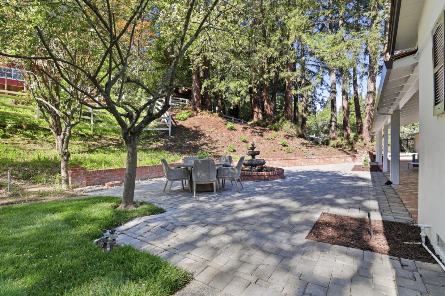 425 Summit Spring Road Woodside, CA 94062 - Photo 30 of 42 a view of a backyard with table and chairs and a large tree