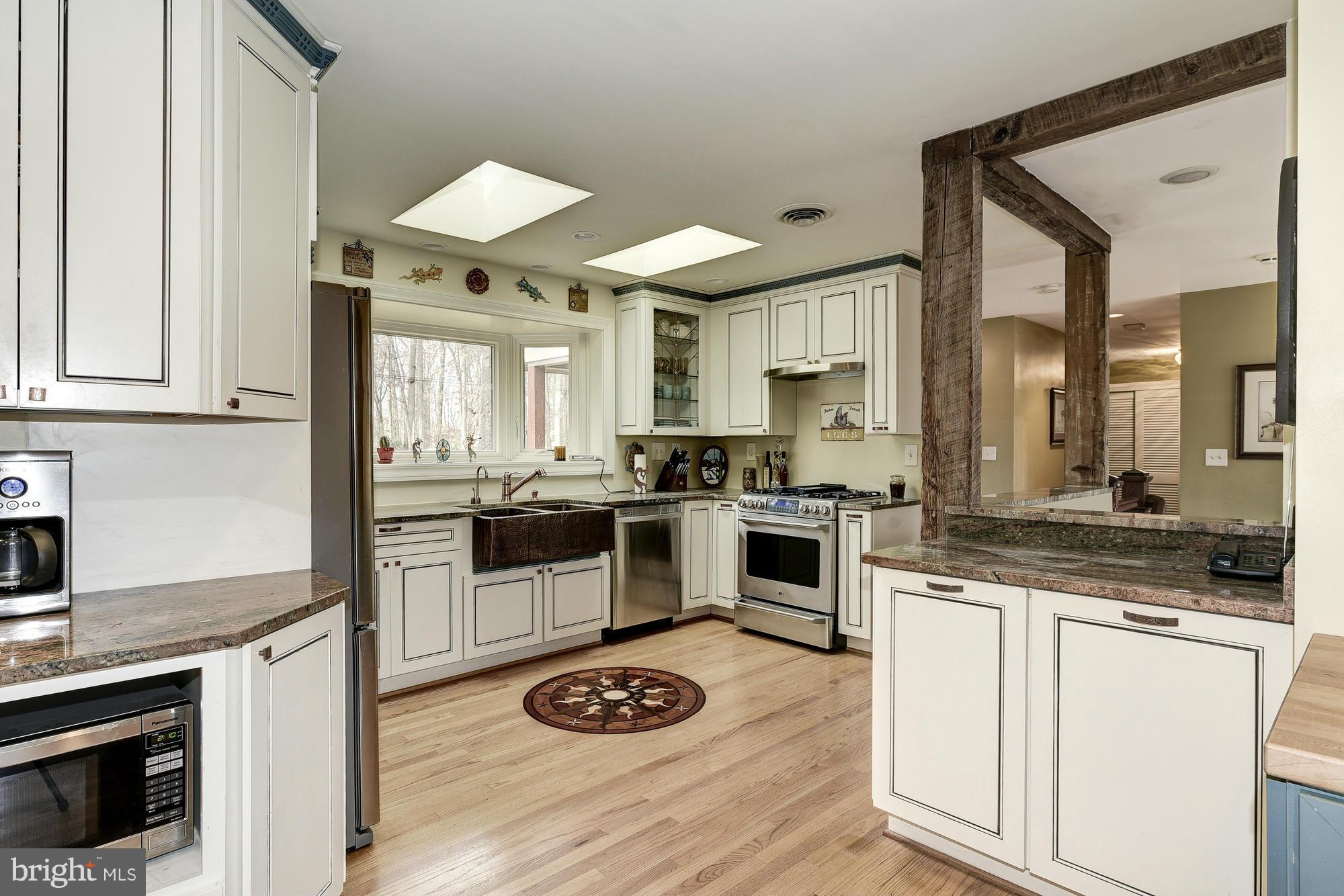 10302 Lloyd Road Potomac, MD 20854 - Photo 9 of 30 a kitchen with granite countertop a stove a sink dishwasher and white refrigerator with wooden floor