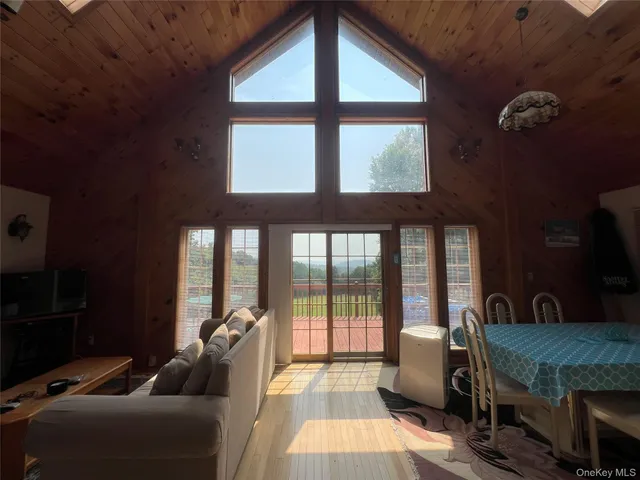 a living room with furniture a flat screen tv and a floor to ceiling window