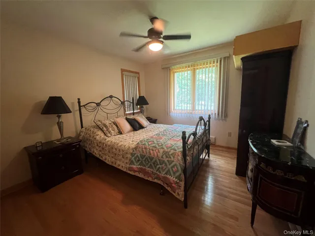 a bedroom with a bed and dresser with wooden floor