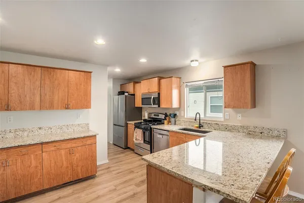 a kitchen with kitchen island granite countertop wooden cabinets a sink and appliances
