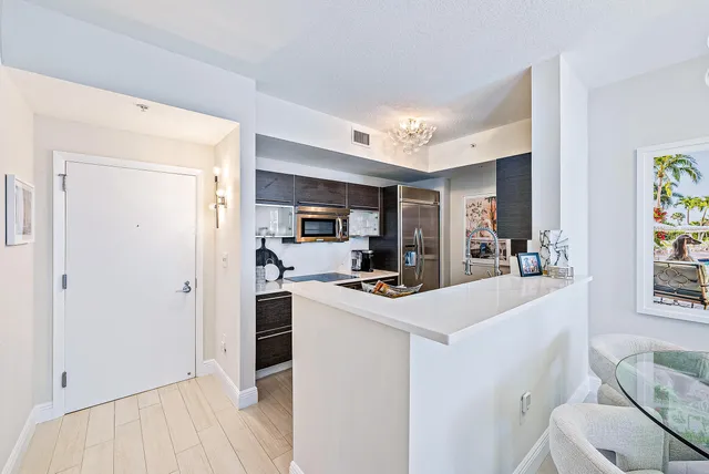 a kitchen with stainless steel appliances a refrigerator a stove a sink a dining table and chairs with wooden floor