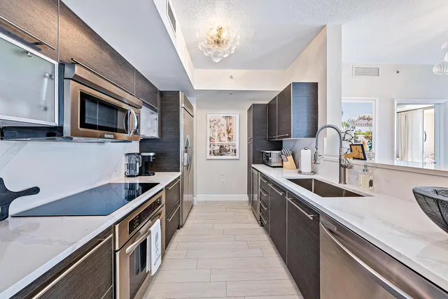 a kitchen with stainless steel appliances granite countertop a sink a stove top oven a refrigerator with wooden floors