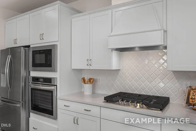 a kitchen with white cabinets and stainless steel appliances
