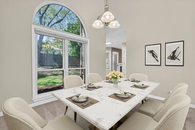 a view of a dining room with furniture a large window a livingroom and chandelier