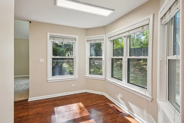 a view of an empty room with a window and wooden floor