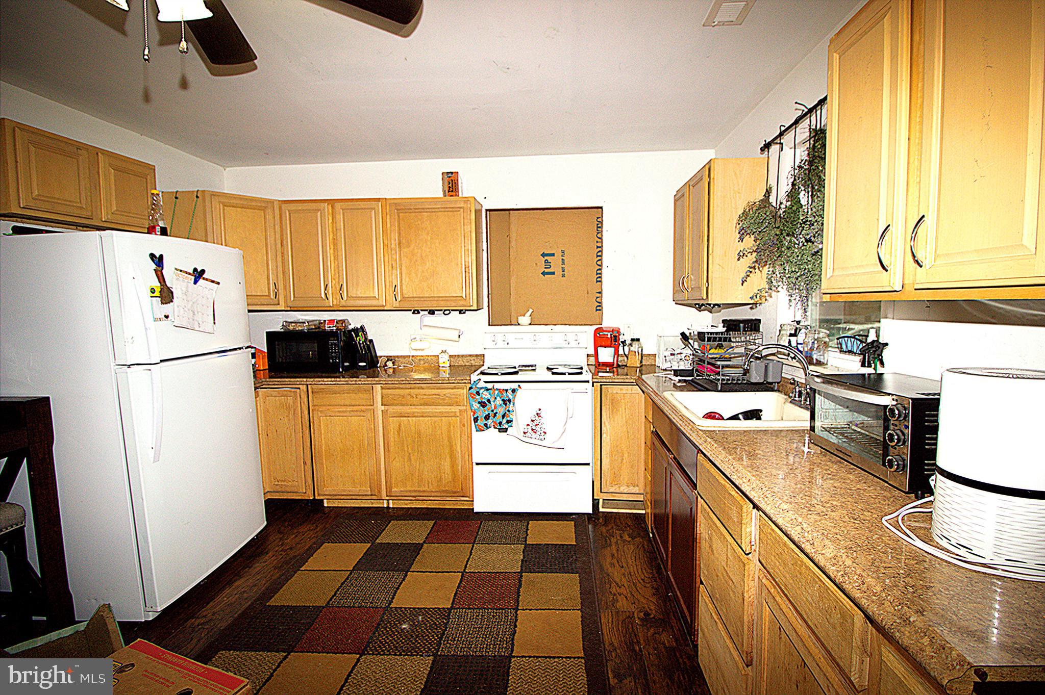 2408 Lodge Farm Road Baltimore, MD 21219 - Photo 2 of 6 a kitchen with a refrigerator a stove a sink dishwasher and wooden cabinets