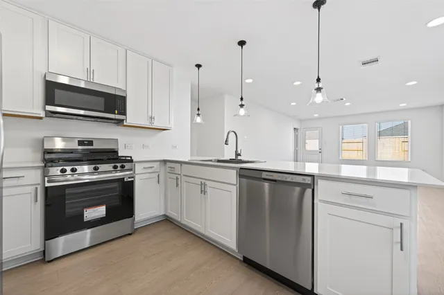 a kitchen with stainless steel appliances granite countertop a sink a stove a microwave and wooden cabinets