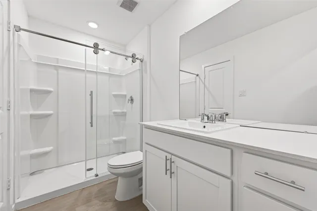 a bathroom with a shower sink vanity mirror and toilet