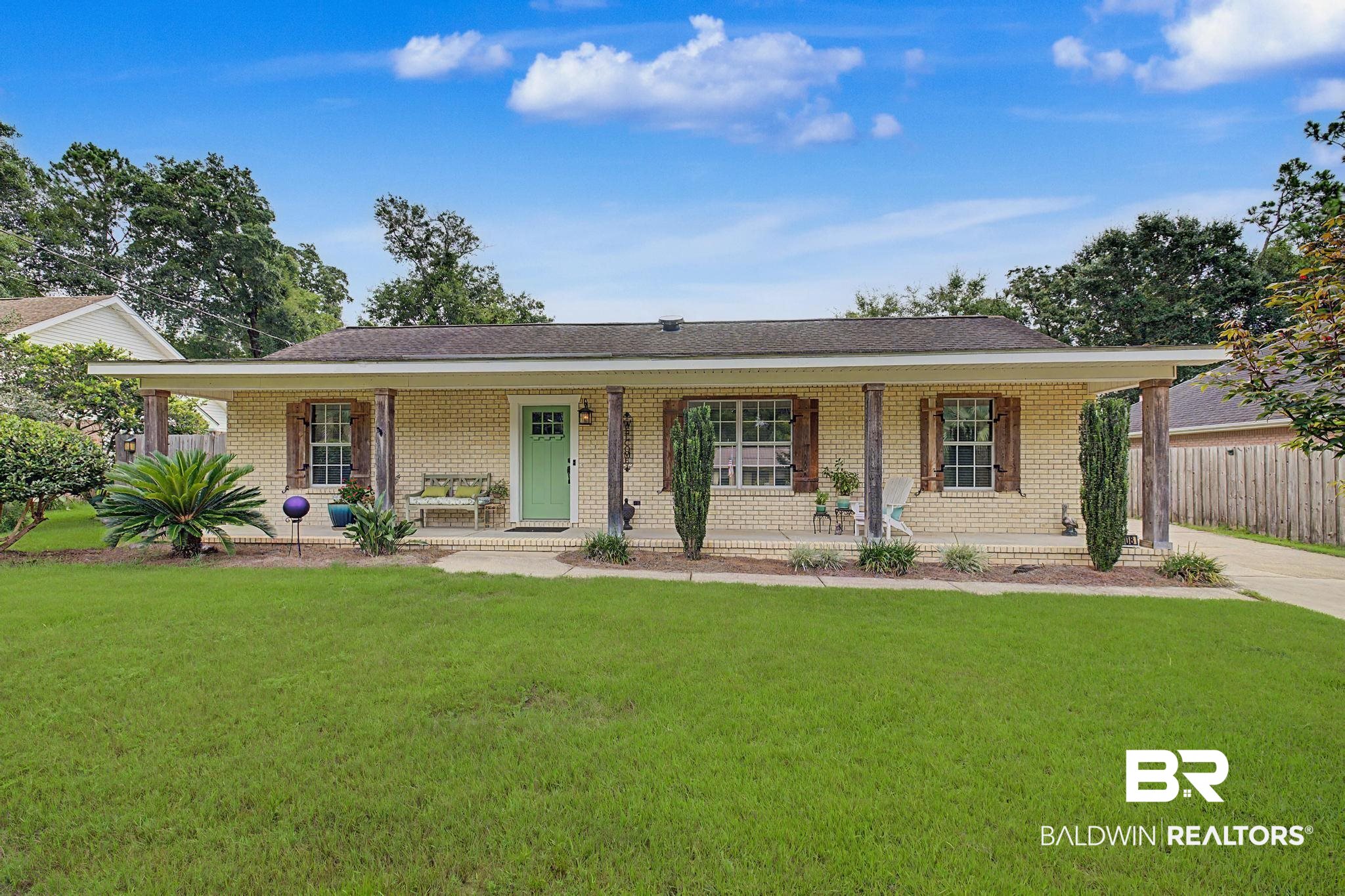 Brick ranch-style residence featuring a welcoming covered porch with wood columns