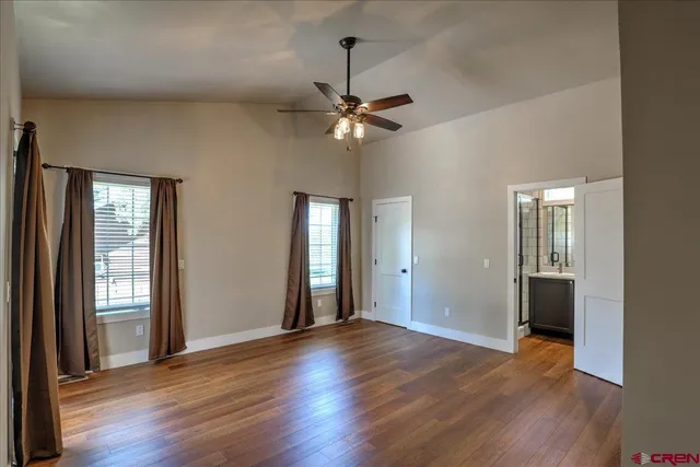 an empty room with wooden floor chandelier fan and windows