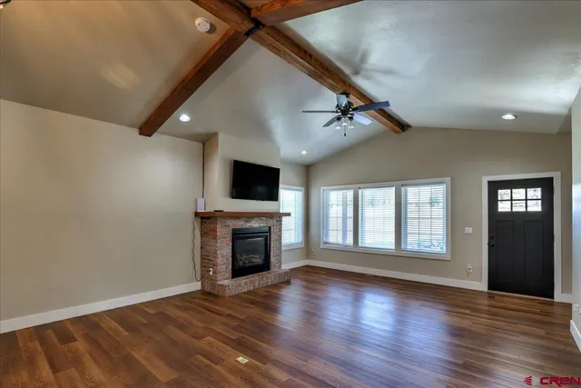 a view of an empty room with wooden floor fireplace and a window