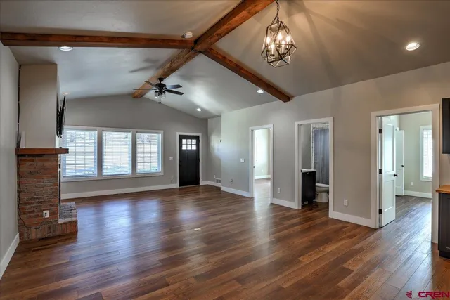 a view of an empty room with wooden floor and a ceiling fan
