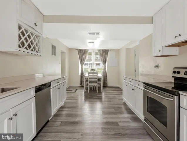 a kitchen with wooden floors and white stainless steel appliances