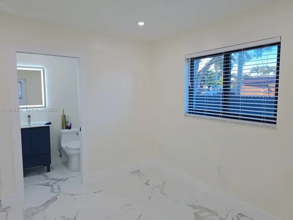 a bathroom with a granite countertop sink a toilet and a window