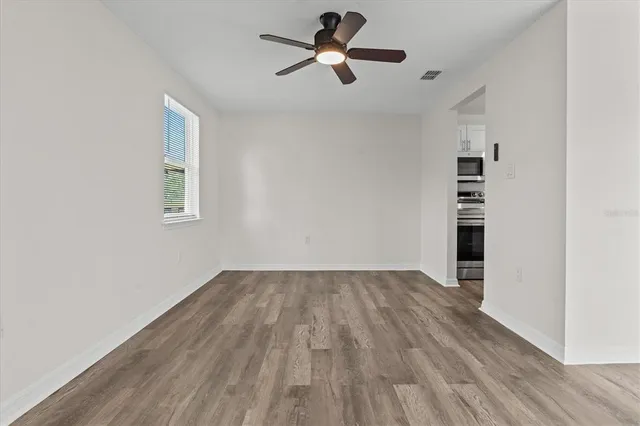 a view of empty room with wooden floor and fan