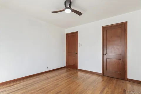 a view of empty room with wooden floor and ceiling fan