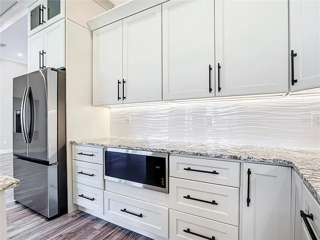 a kitchen with granite countertop a sink and dishwasher a refrigerator with wooden cabinets