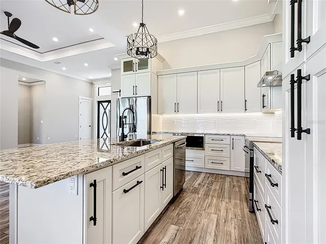 a kitchen with stainless steel appliances kitchen island granite countertop a stove refrigerator and cabinets