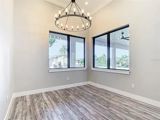 a view of empty room with wooden floor and chandelier