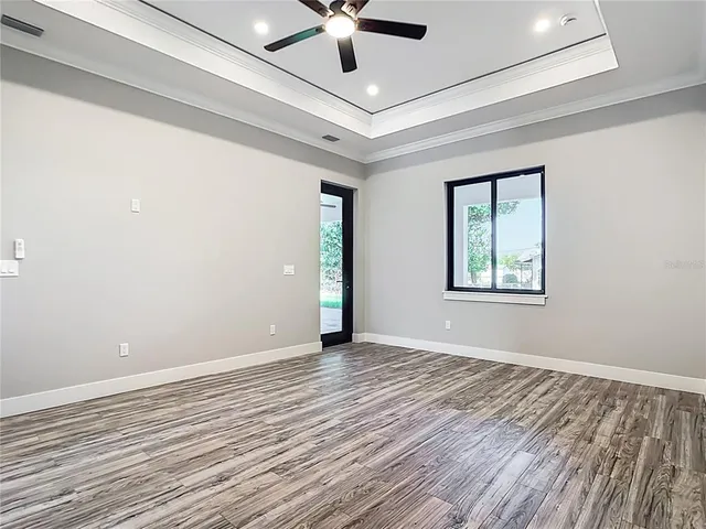 a view of an empty room with window and wooden floor