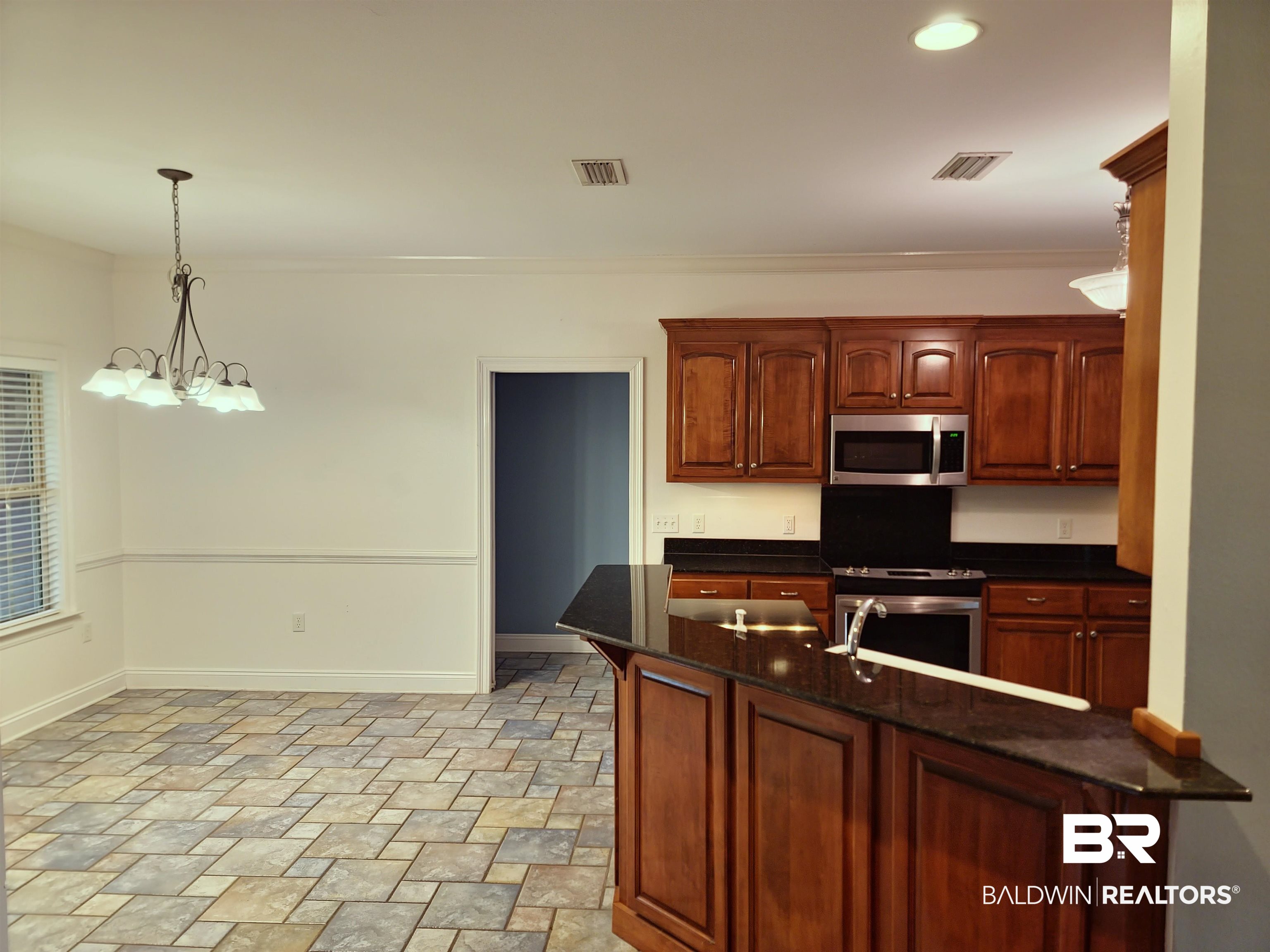 306 South Tee Drive Fairhope, AL 36532 - Photo 14 of 37 Kitchen with kitchen peninsula, appliances with stainless steel finishes, crown molding, pendant lighting, and an inviting chandelier