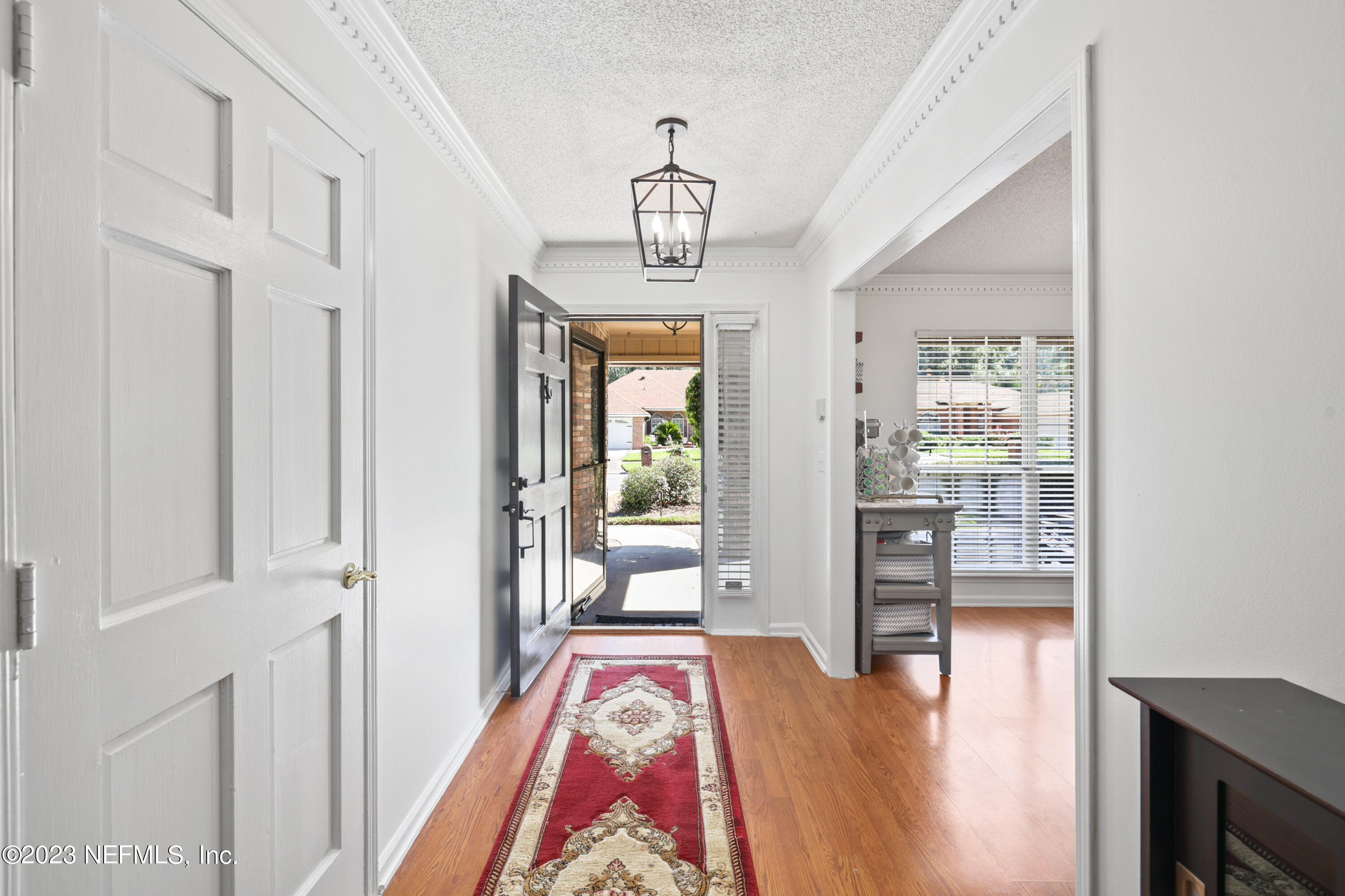 10954 Heathfield Road Jacksonville, FL 32225 - Photo 5 of 42 a view of a hallway with wooden floor and a chandelier
