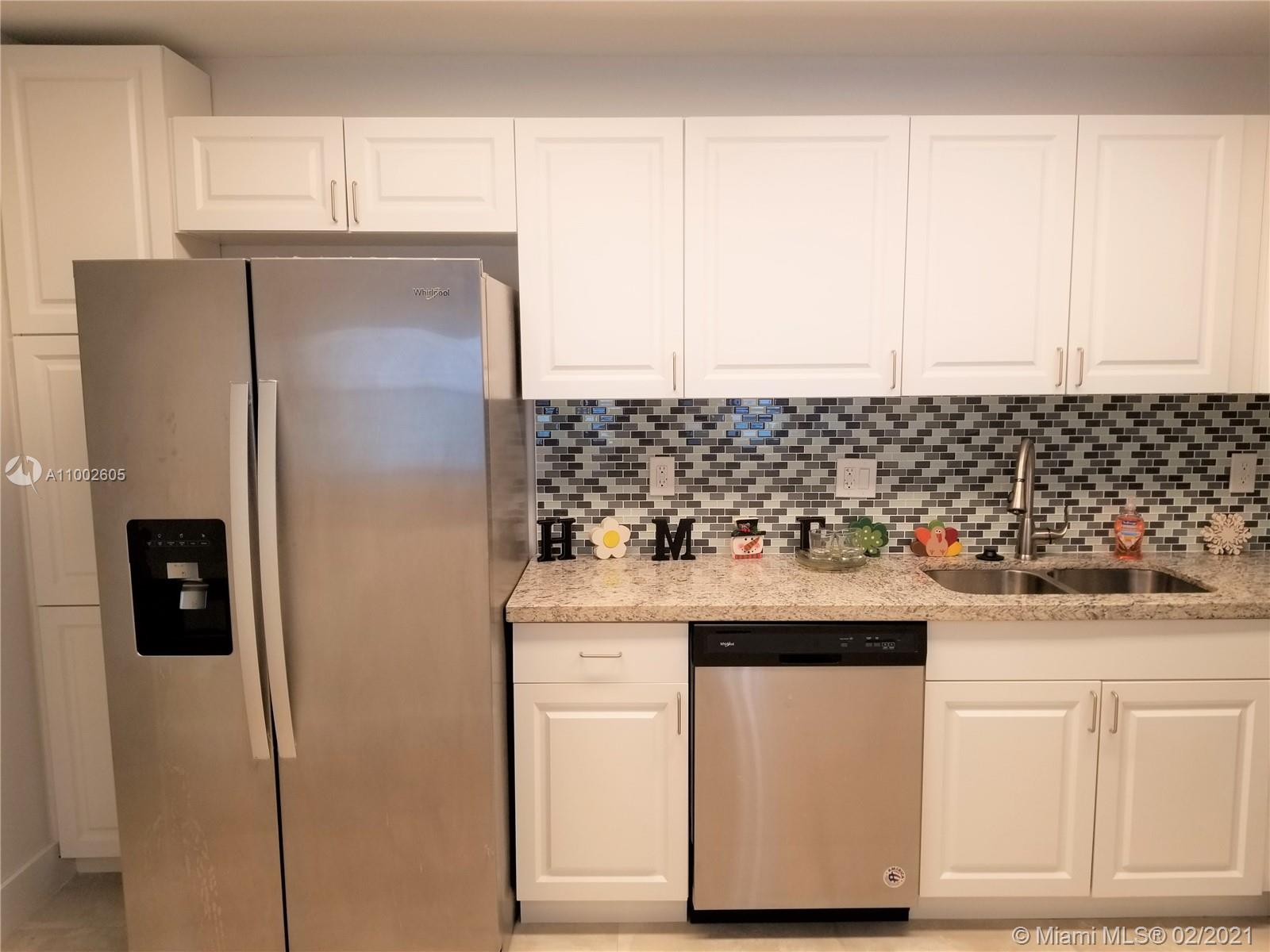 a kitchen with stainless steel appliances granite countertop white cabinets and refrigerator