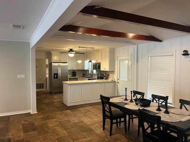 a kitchen with a dining table chairs and white cabinets