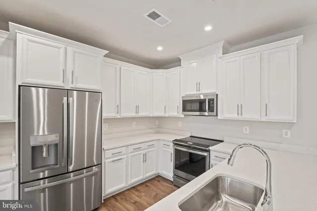 a kitchen with stainless steel appliances white cabinets and a refrigerator
