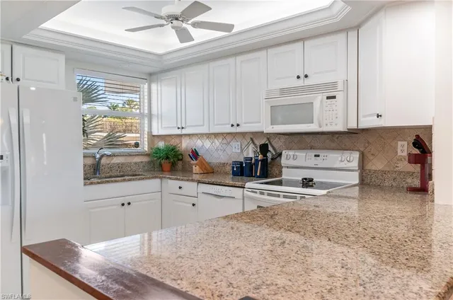 a kitchen with granite countertop a stove a sink and a white cabinets