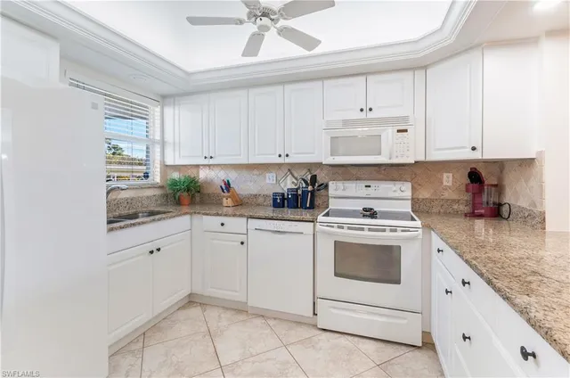 a kitchen with granite countertop white cabinets white stainless steel appliances and sink